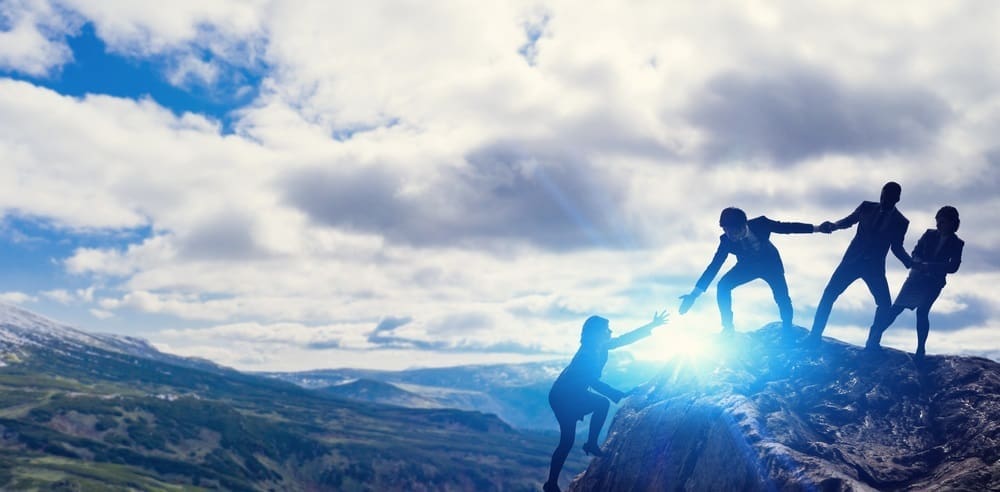 business people reaching the peak of a mountain